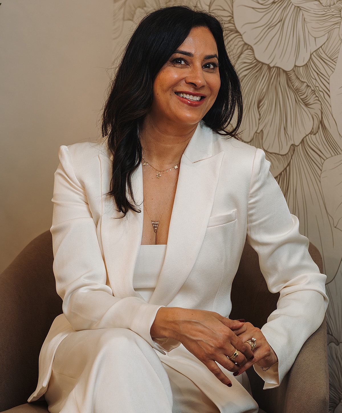 Smiling woman in elegant white suit, sitting.