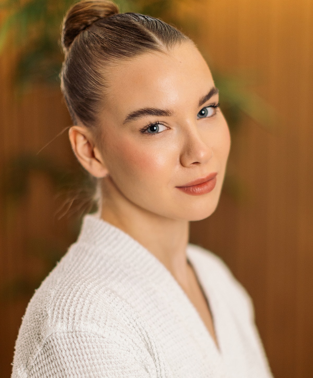 Smiling woman with a bun hairstyle indoors.