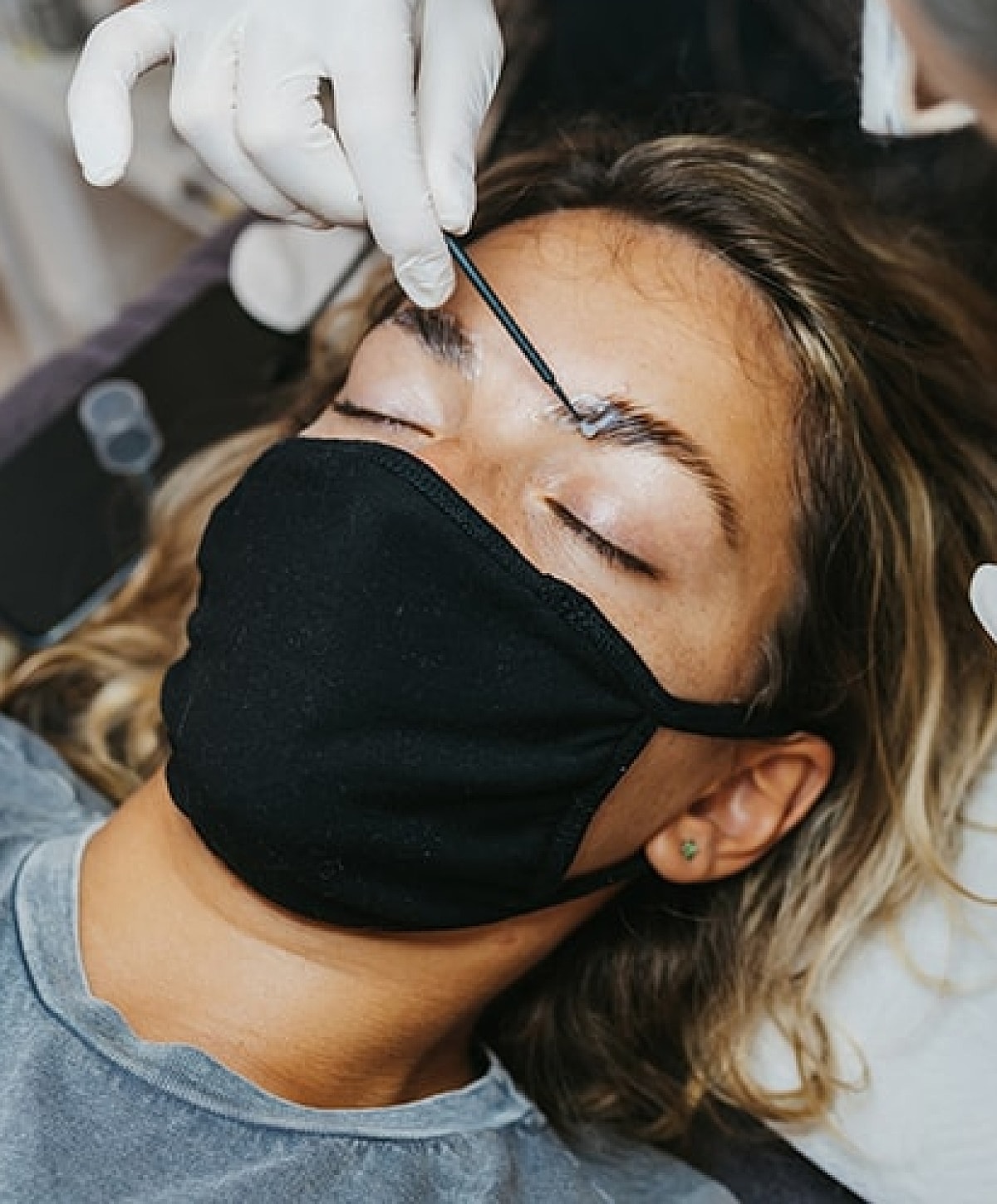 Eyebrow treatment in progress with protective mask.
