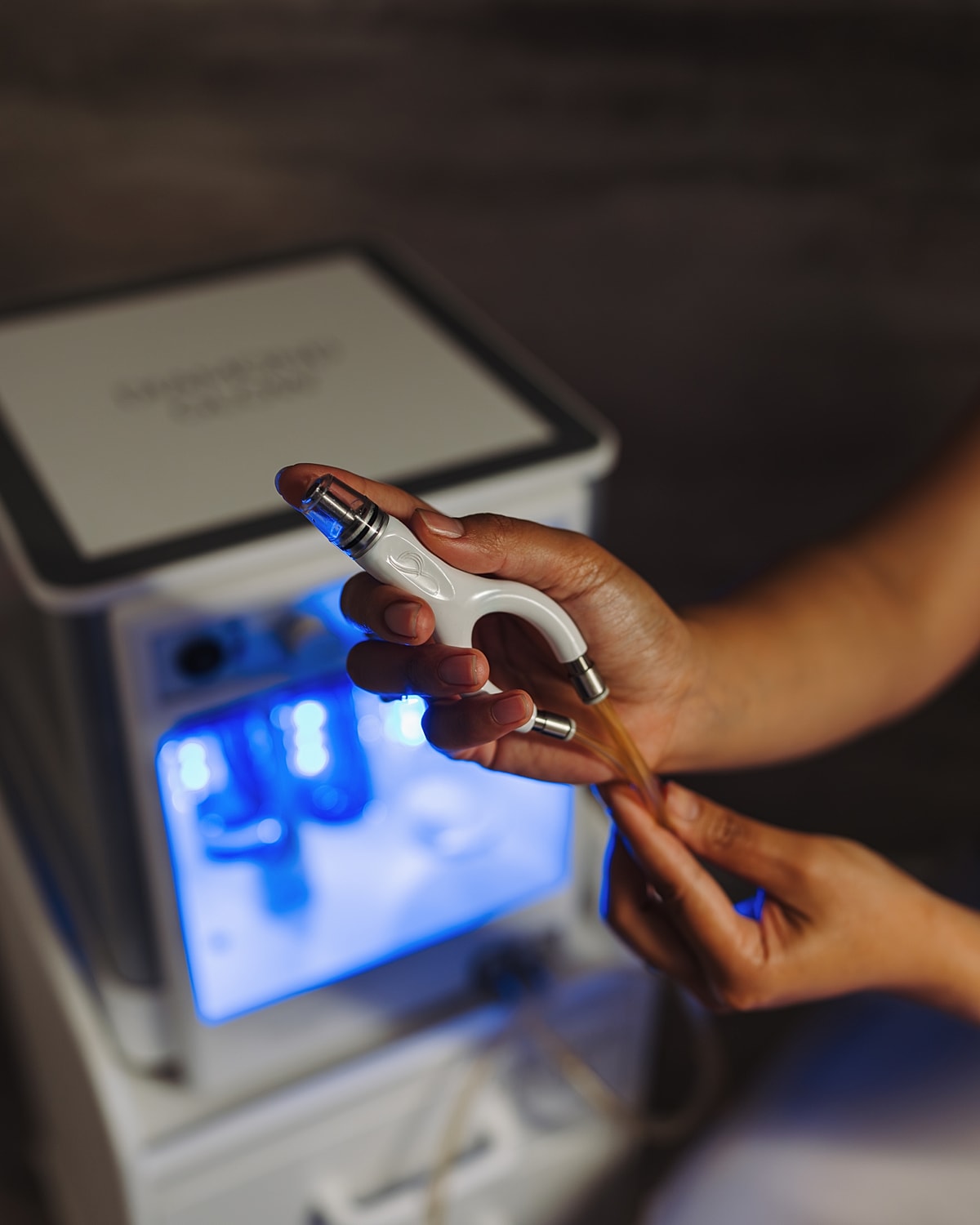Hand holding a beauty device with tubing.