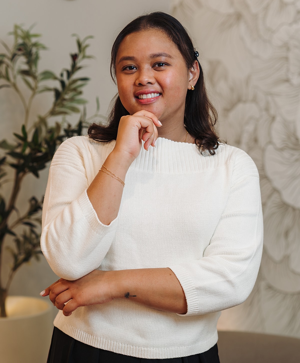 Smiling woman in white sweater, thoughtful pose.
