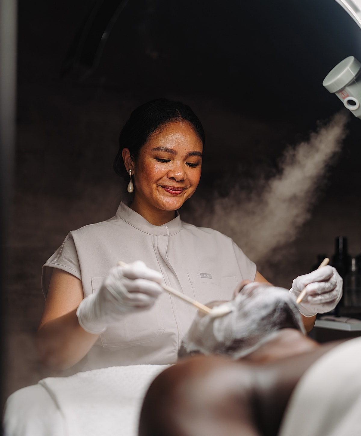 Esthetician applying facial treatment to a client.
