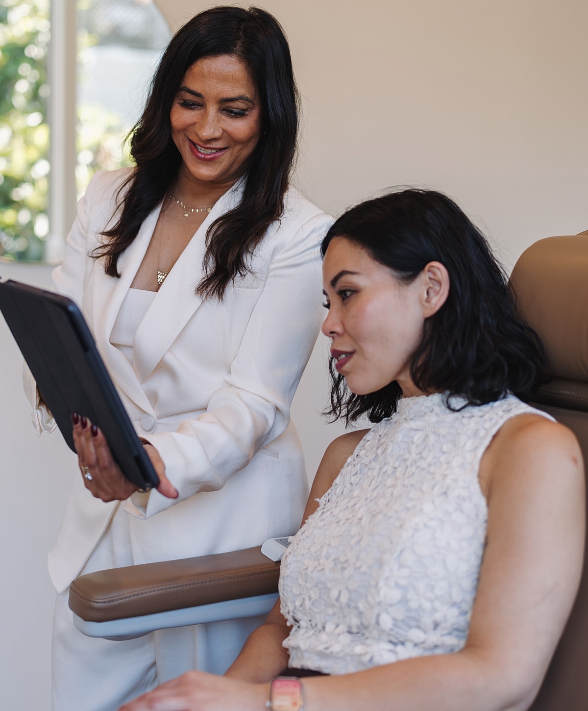 Women discussing a tablet in a professional setting.
