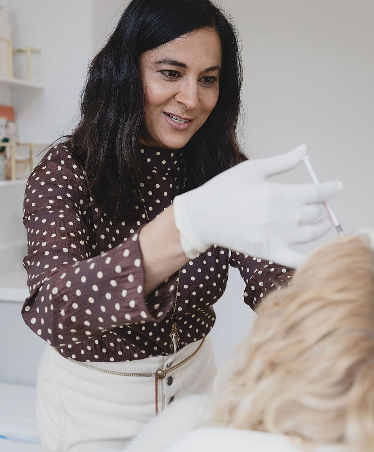 Practitioner applying treatment on client's hair.