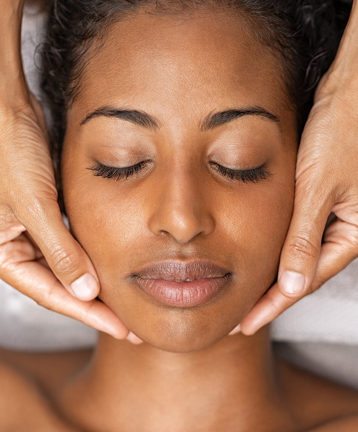 Facial massage therapy session with relaxed client.
