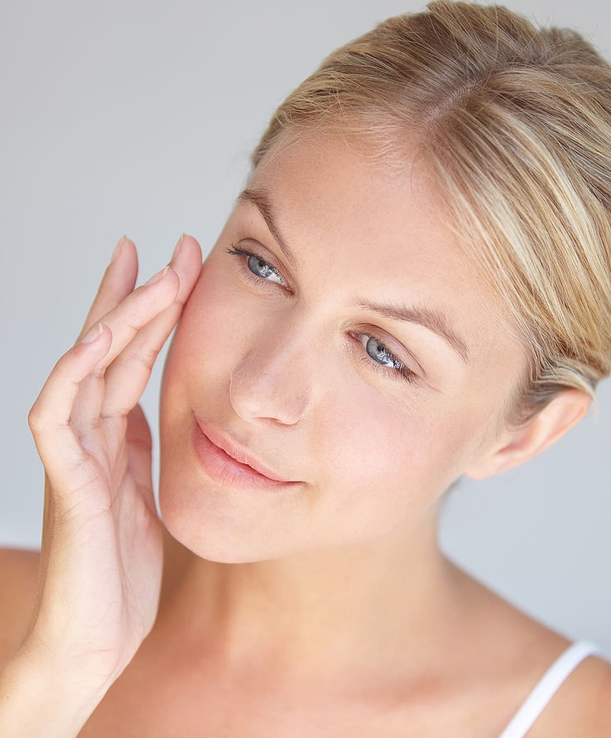 Woman applying skincare on her face gently.