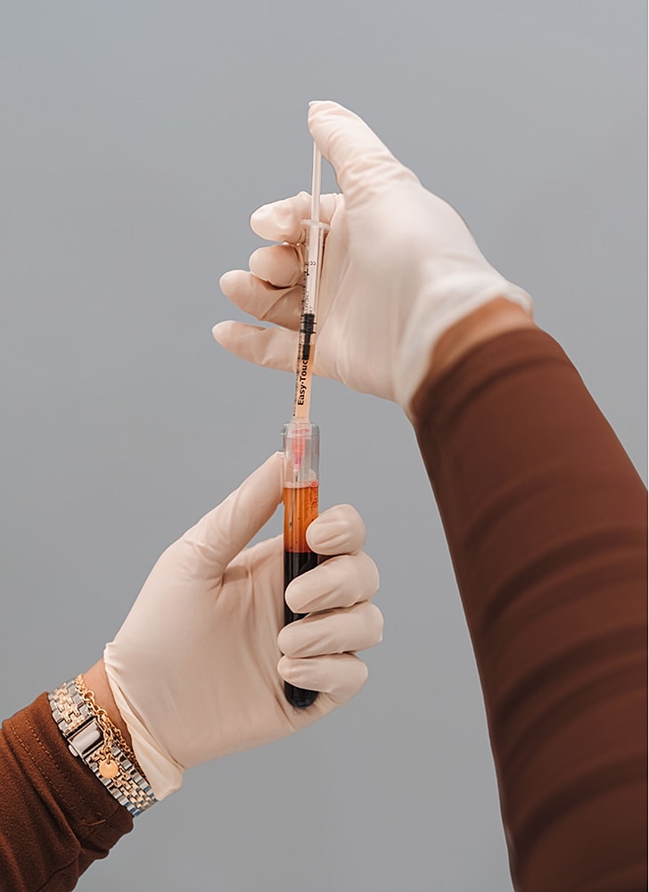 Person holding syringe with blood sample.