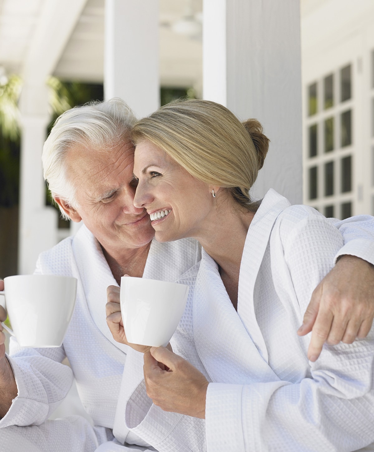 Couple enjoying coffee in bathrobes outdoor.