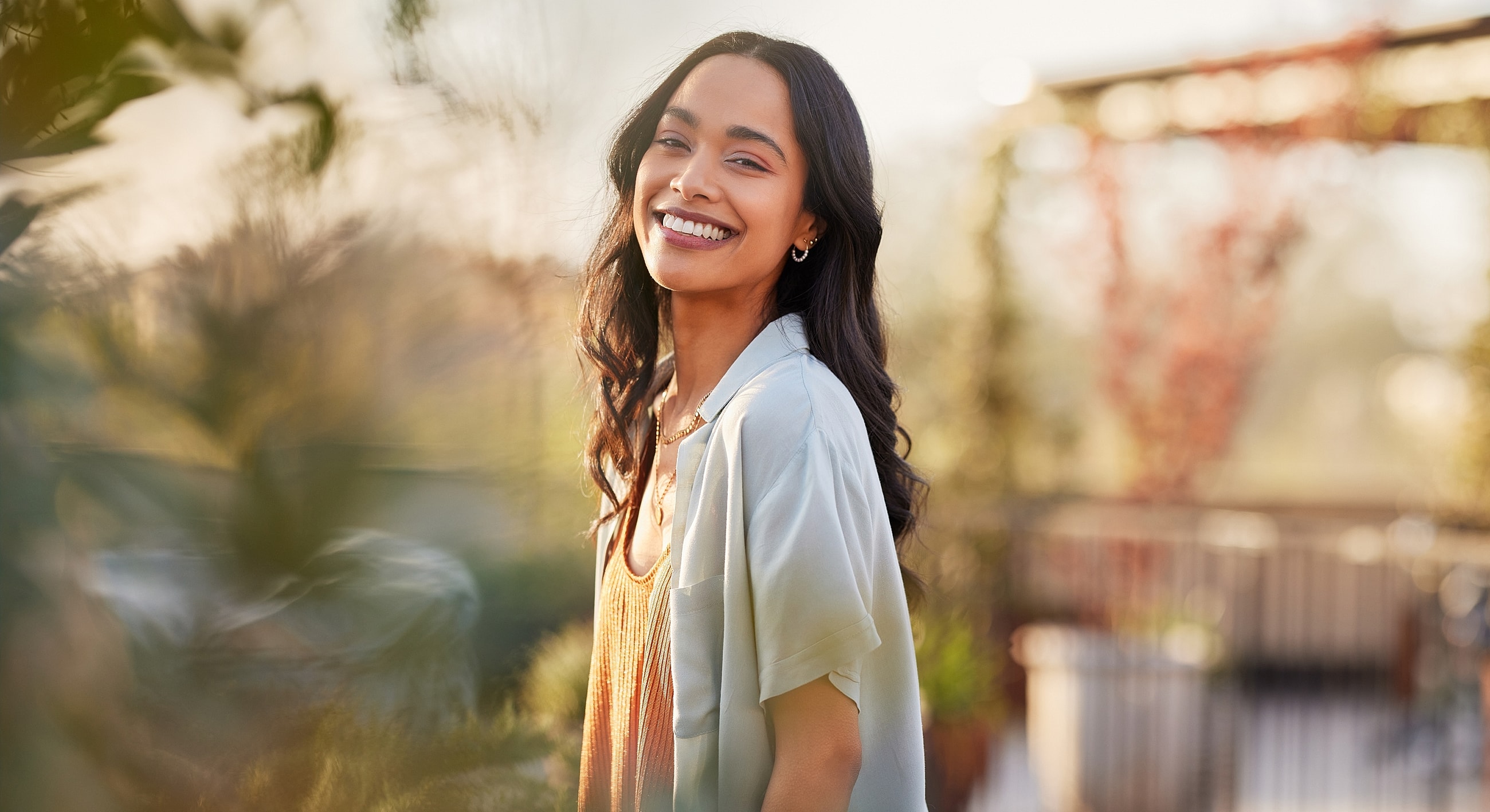 Smiling woman outdoors in soft, natural light.